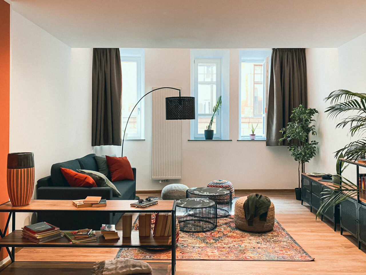 Heller Wohnraum mit Sofa, Teppich und hohen Fenstern