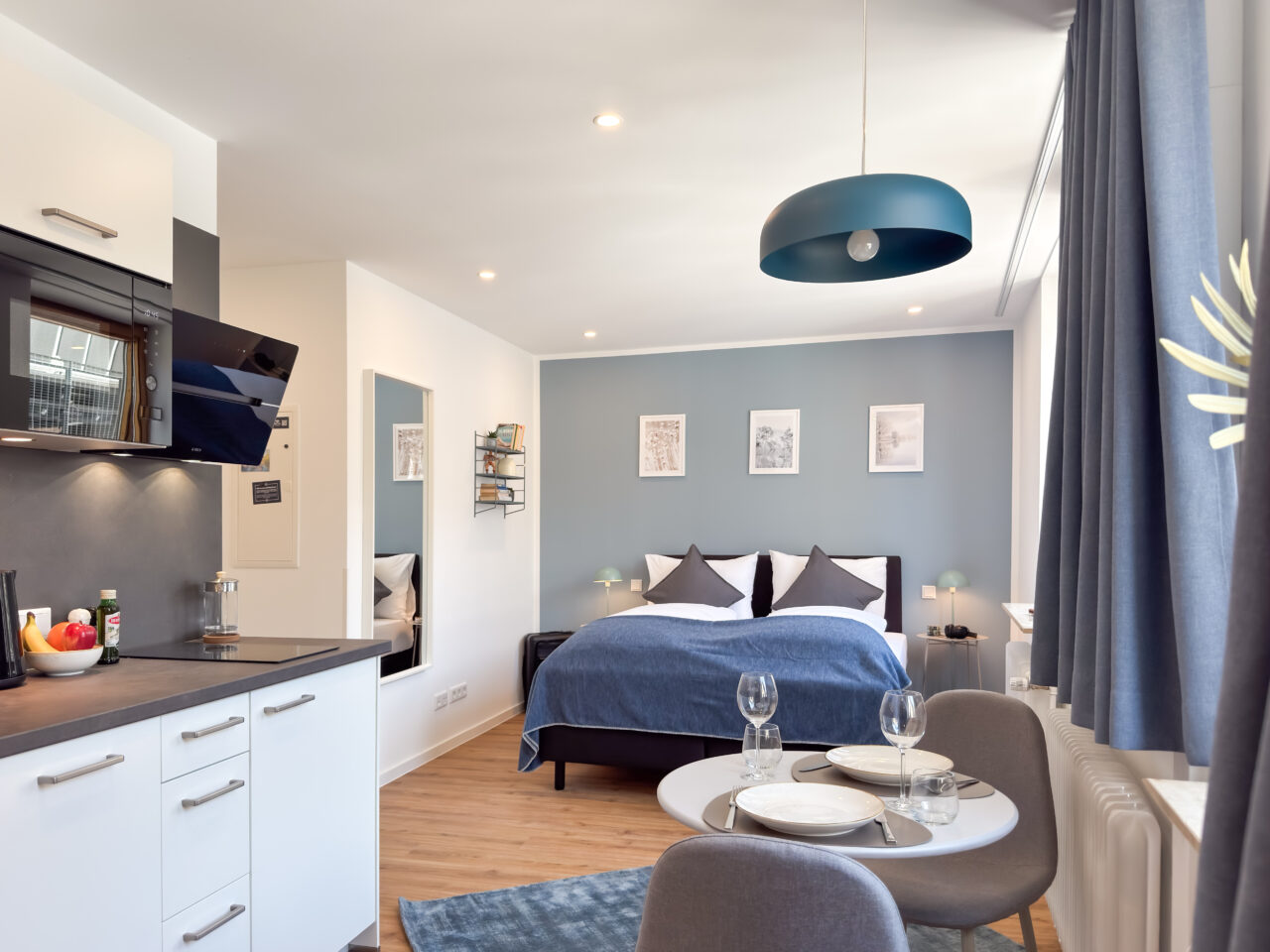 Bett mit dunkelblauer Decke vor einer blaugrauen Wand